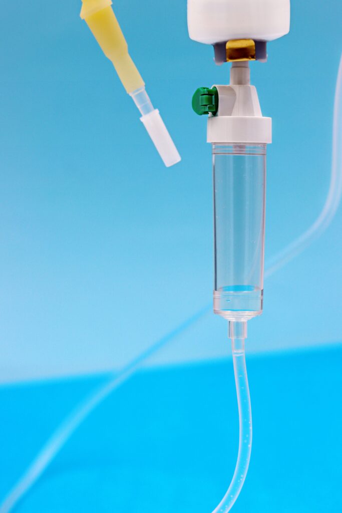 Detailed view of an IV drip setup on a pale blue background, ideal for medical and healthcare themes.